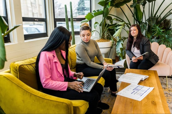 Three colleagues sit on couch in discussion